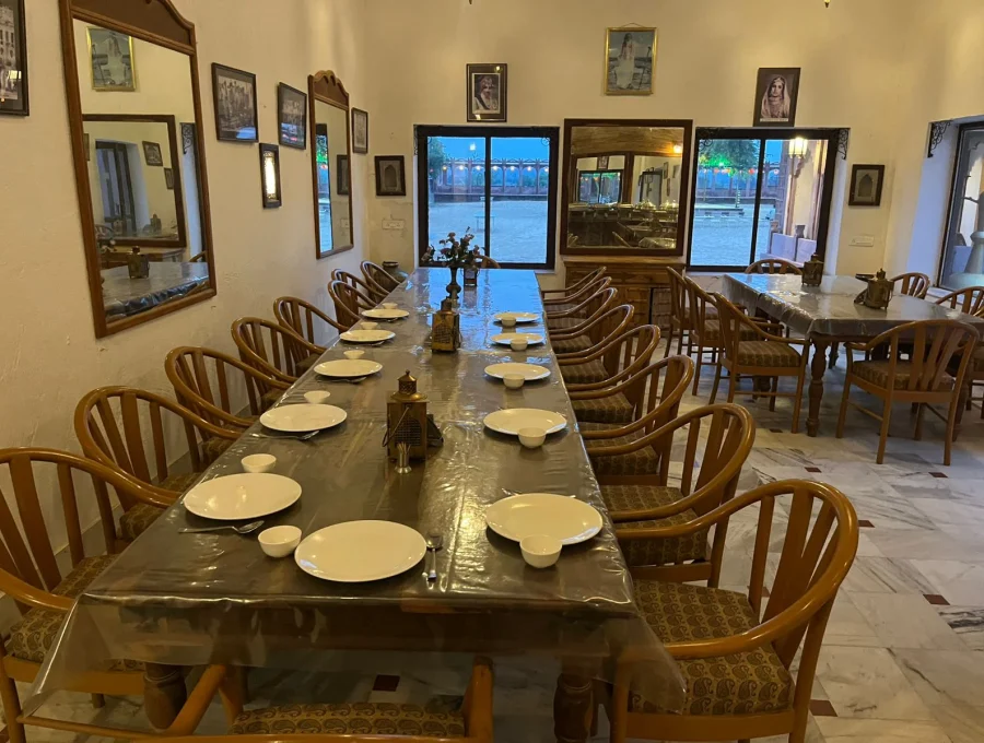 Indoor dining hall with rustic wooden tables set for traditional Rajasthani vegetarian lunch in Osian