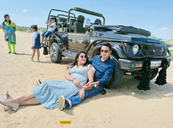 Couple sitting on open safari jeep parked on sand dunes in Osian