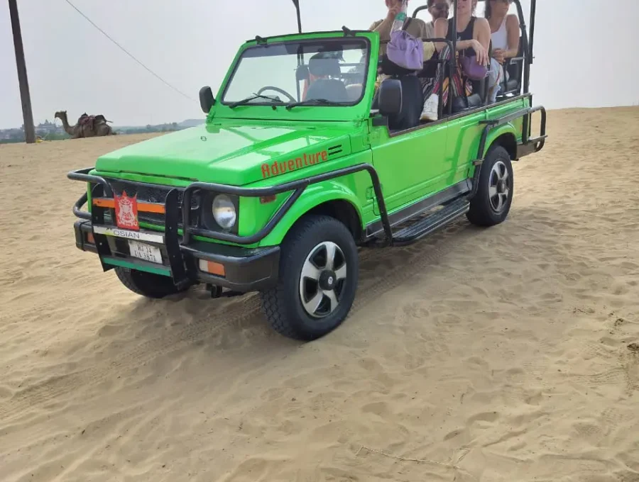 Open 4x4 safari jeep navigating desert sand dunes during afternoon safari in Osian
